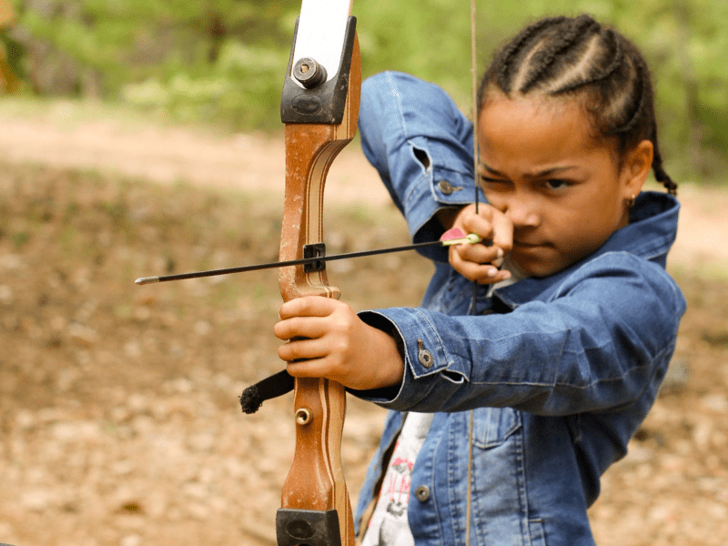 Jeune enfant qui s'exerce à la pratique du tir à l'arc durant la colonie de vacances multi activités Montagne Nature à Paques