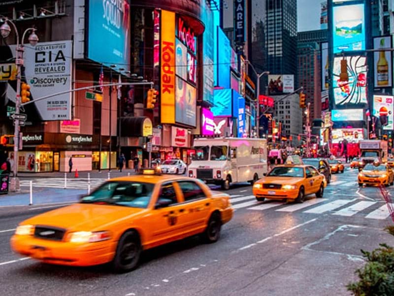 Grande rue animée de New York avec ses célèbres taxis et néons lors d'une colo de vacances pour ados au printemps