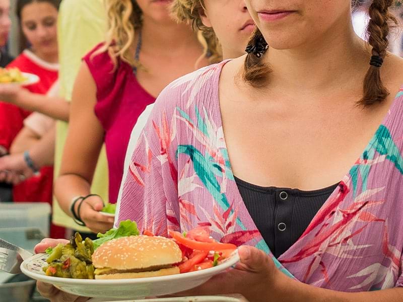 Jeune fille qui se sert un hamburger lors d'un repas en colo de vacances à New York au printemps