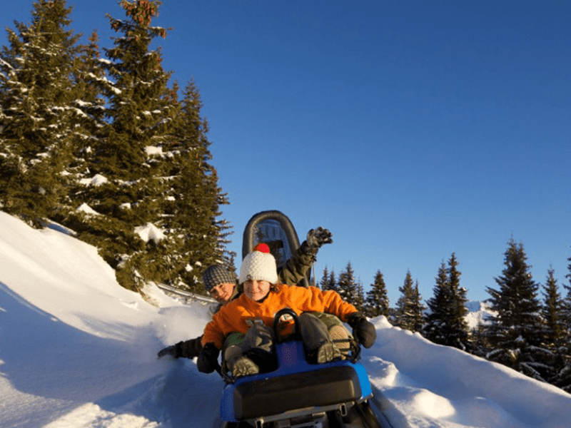 Deux jeunes en colo de vacances à la montagne descendent une piste de luge sur rails, Mountain Twister, en colo