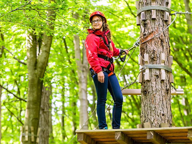 Jeune fille qui fait de l'accrobranches en colo de vacances à Monistrol au printemps