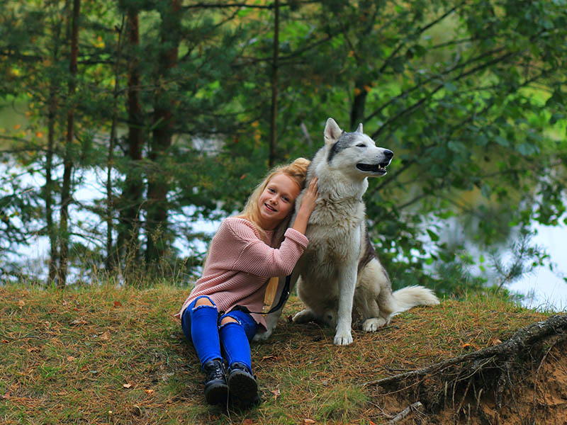 Jeune fille, complice avec son chien, durant l'activité cani rando en colo de vacances