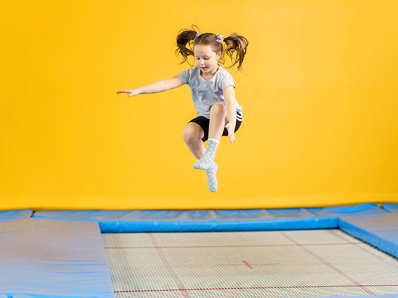 Jeune fille qui saute en trampoline en colo de vacances ce printemps