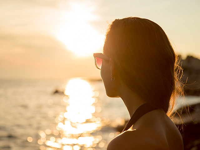 Jeune ado qui observe le coucher de soleil en colo de vacances à Minorque
