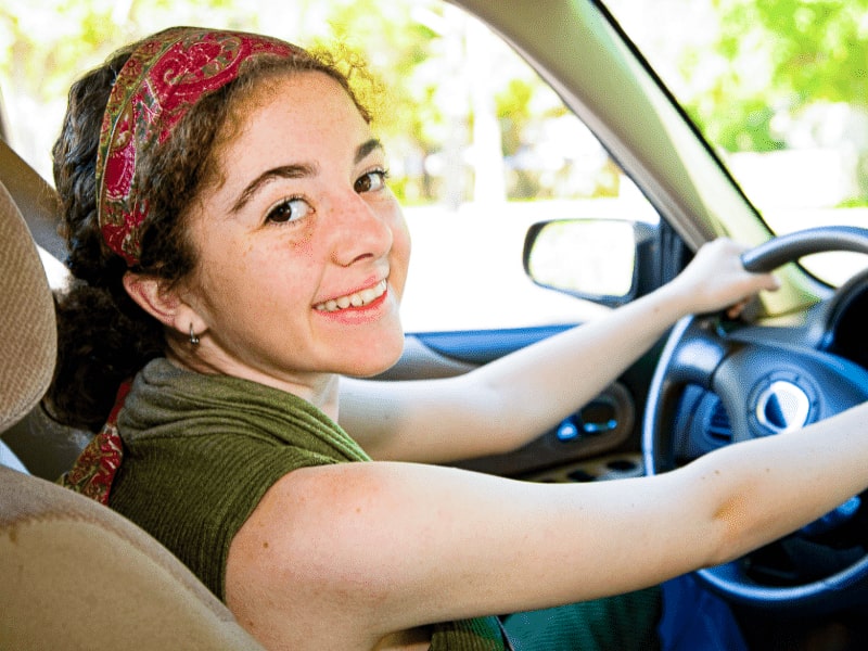 Jeune fille qui sourit et qui est heureuse de conduire en colo de vacances conduite accompagnée ce printemps en colo