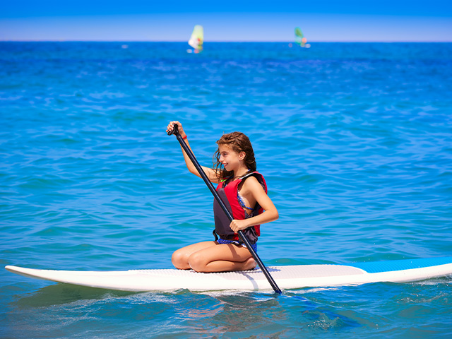 fille sur son paddle sur une eau bleue en grece colo de vacances ados