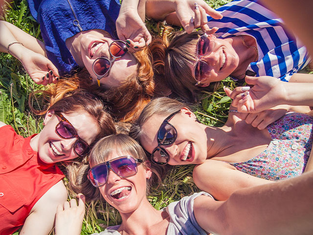 jeunes filles allongees sur l'herbe se prenant en photo colonie de vacances adolescents avril
