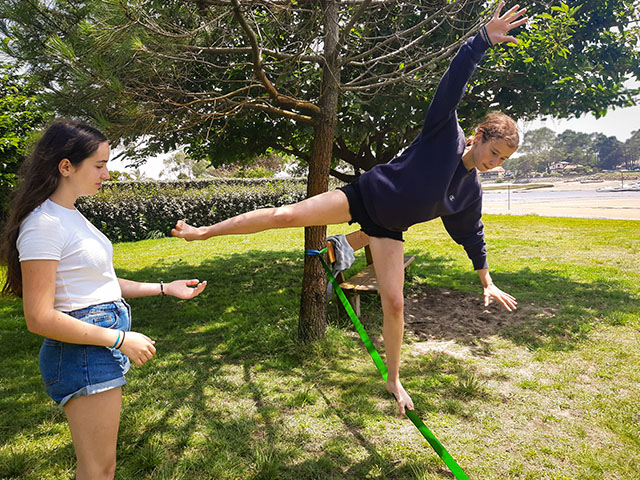 deux filles sur une slackline s'amusant a tenir en equilibre pendant qu'une autre regarde sejour a la montagne au printemps  