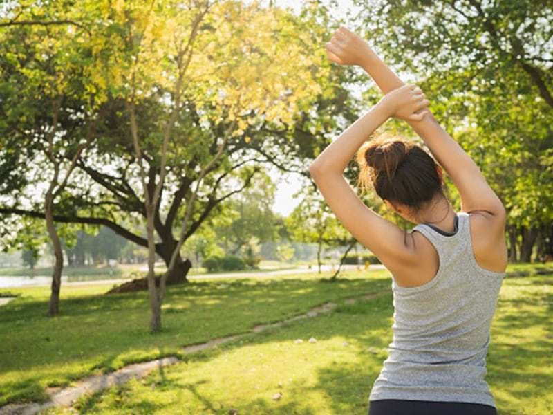 Personne qui s'étire pendant une séance de yoga en pleine nature lors d'une colonie de vacances Corps et Esprit