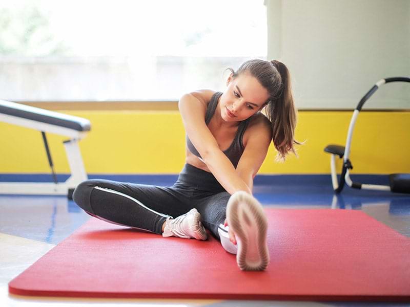 Jeune fille qui s'étire après sa séance de sport lors d'une colonie de vacances Corps et Esprit durant le printemps