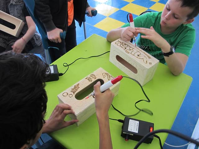 Enfants pratiquant la pyrogravure en colo