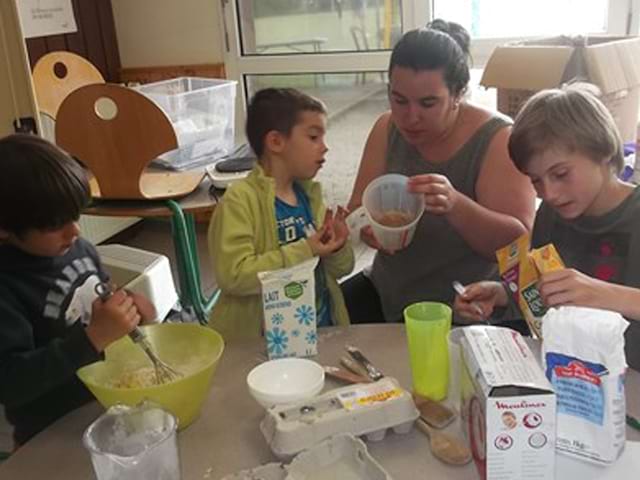 Groupe d'enfants apprenant à cuisiner avec une animatrice de colo