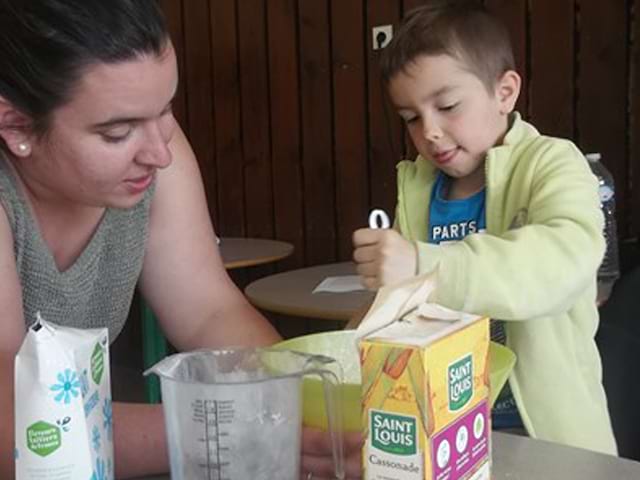 Enfant et son animatrice lui apprenant à cuisiner