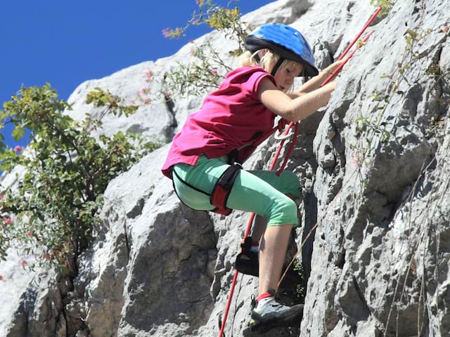 Enfant pratiquant l'escalade en colonie de vacances au printemps