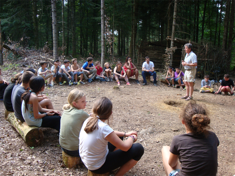 Groupe d'enfants en cercle dans la forêt écoutant une histoire
