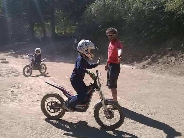 Enfant roulant à moto guidé par l'animateur de colo