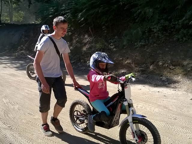 Enfant apprenant à faire de la moto grâce à son animateur de colonie