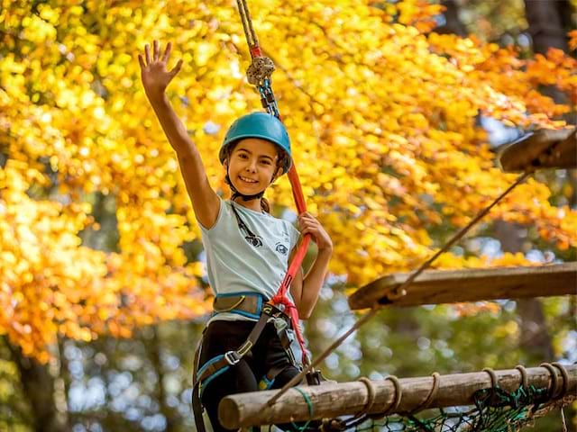 Jeune fille pratiquant l'accrobranche en colonie de vacances à Eco park