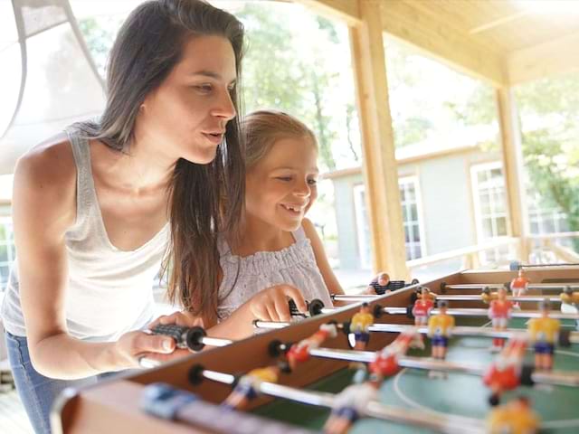 Enfant et son animatrice de colonie de vacances jouant au babyfoot en vacances