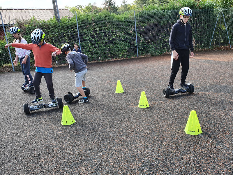 Enfants apprenant à conduire un hoverboard sur un parcours d'obstacles