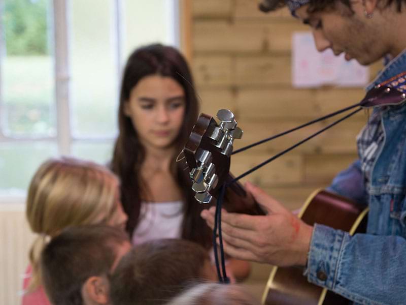 Animateur de colo jouant de la guitare en colonie de vacances