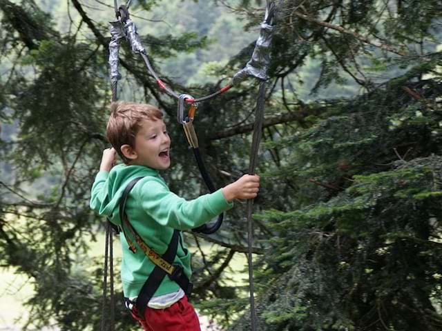 Enfant faisant de l'accrocbranche en colo