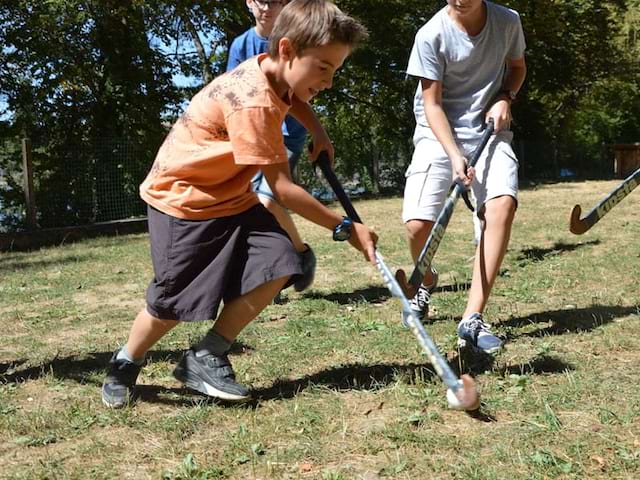 Enfants jouant ensemble au hockey sur gazon en colonie de vacances