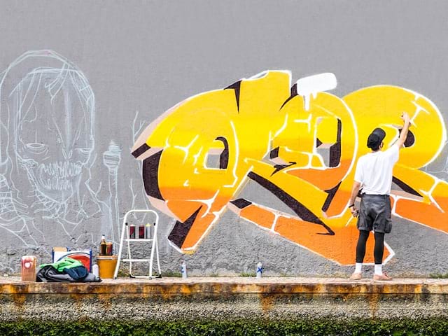 Graffeur qui décore un mur dans une rue street Art à Berlin en Allemagne