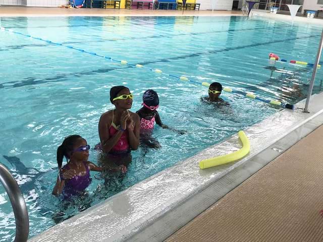 groupe d'enfants dans la piscine apprenant à nager avec des frites en colonie de vacances