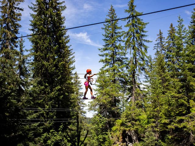 adolescente faisant de l'accrobranche en colonie de vacances à la montagne