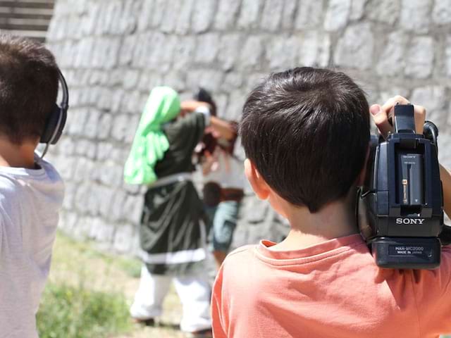 enfant tenant sur son épaule une caméra lors de la réalisation d'un court métrage en colonie de vacances