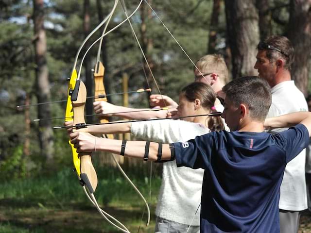 groupe d'enfant apprenant à faire du tir à l'arc cet automne en colonie de vacances à la montagne