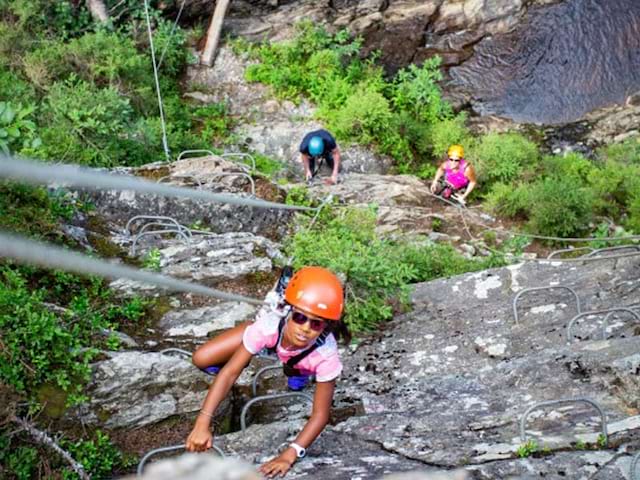 Enfant faisant de la via ferata en colonie de vacances à la montagne