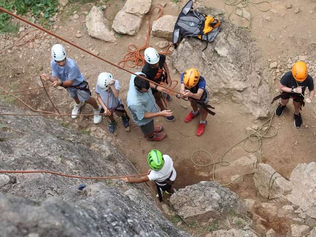 groupe d'enfants pratiquant la descente en rappel en colonie de vacances à la montagne