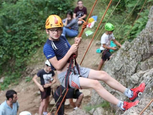 Enfant faisant de l'escalade en colonie de vacances à la montagne