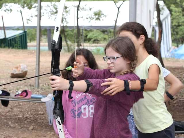 fillette apprenant à faire du tir à l'arc sécurisé en colo cet automne