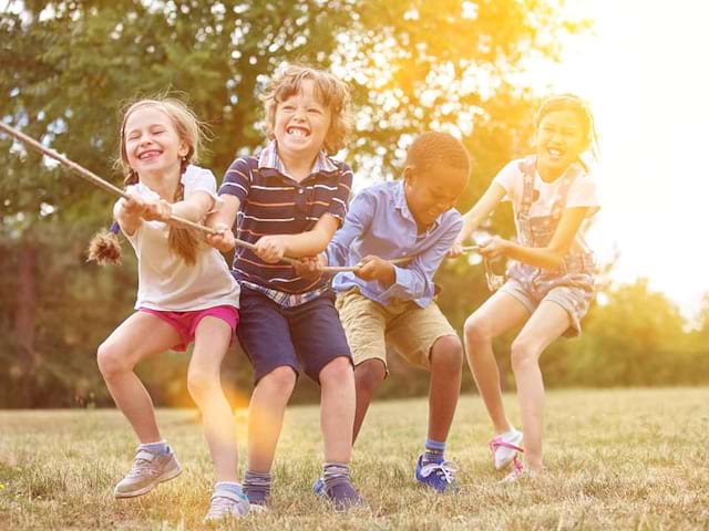 quatre enfants jouant à la corde en colonie de vacances à la montagne