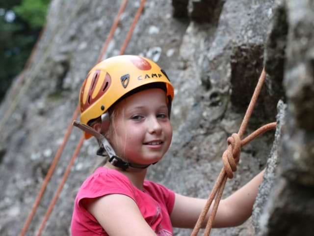 portrait d'une fillette faisant de l'escalade en colonie de vacances à la montagne