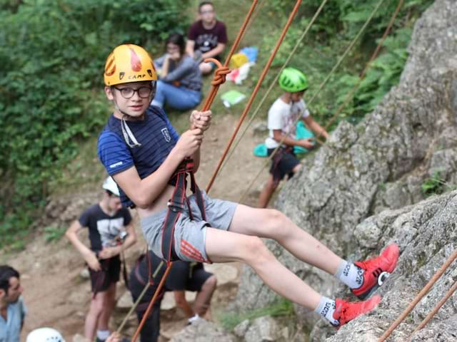 jeune garçon en descente en rappel en colonie de vacances à la montagne