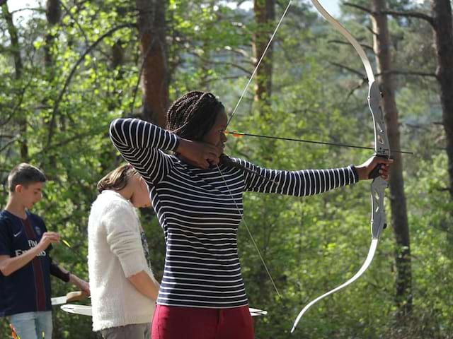 jeune adolescente se perfectionnant au tir à l'arc en colonie de vacances à la montagne