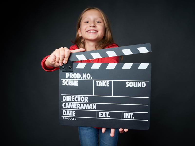 fillette tenant un clap de cinéma durant une colonie de vacances cinema