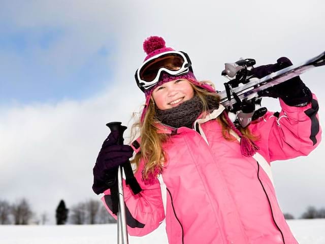 jeune fille avec son équipement de ski sur les pistes de colonie de vacances