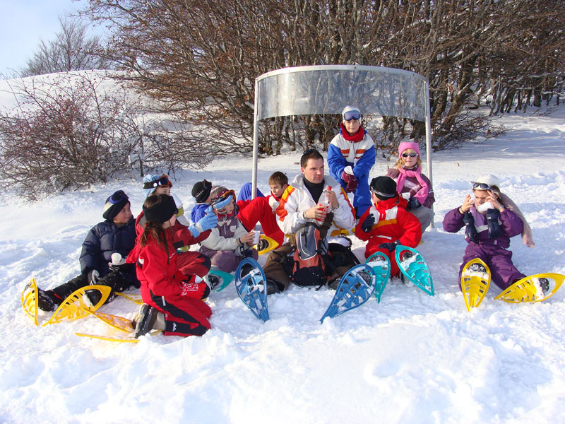 groupe d'enfants assis dans la neige en colonie de vacances