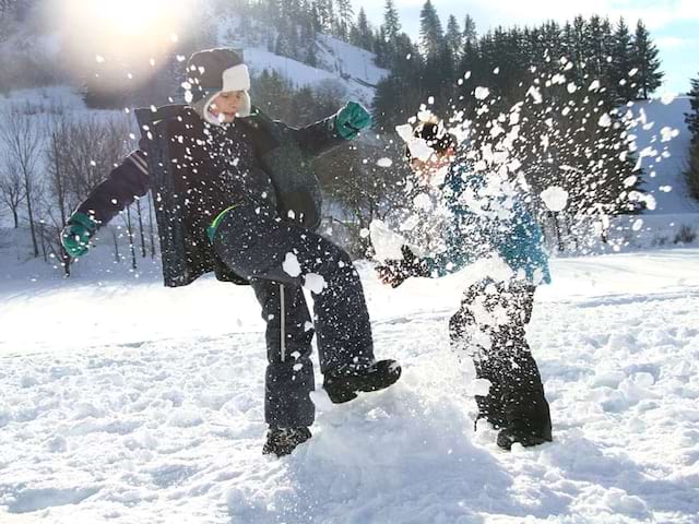 enfants jouant avec la neige en colonie de vacances