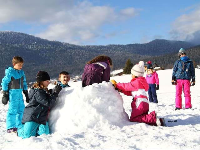 enfants construisant un igloo en colo cet hiver