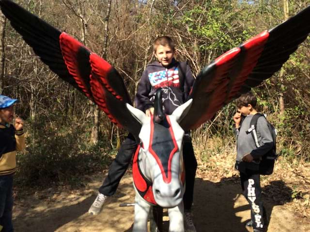 Enfant sur une statue de cheval ailé à Défi'planet en colonie de vacances cet automne