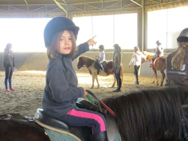 Enfant apprenant à faire du poney en colonie de vacances à la toussaint