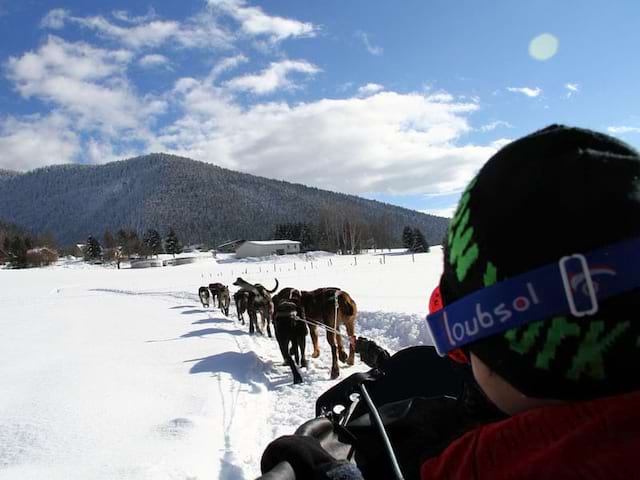 Enfant sur un traineau en balade à la montagne en colonie de vacances