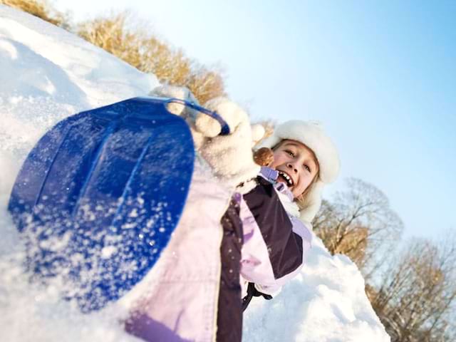 jeune fille faisant de la luge en colo cet hiver