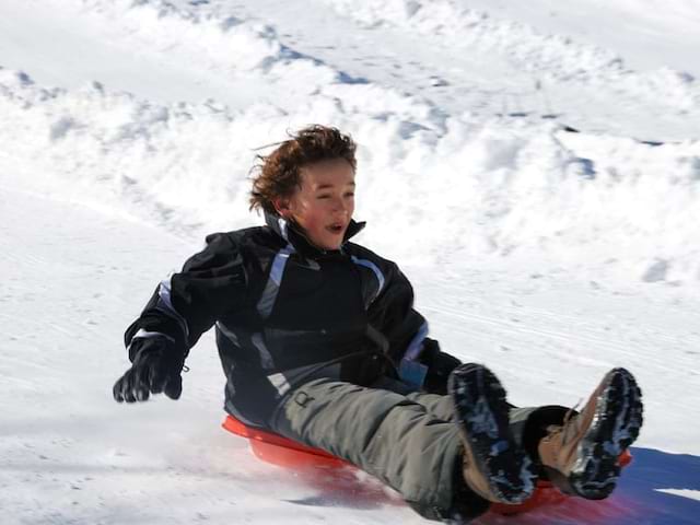 enfant faisant de la luge sur les pistes en colonie de vacances